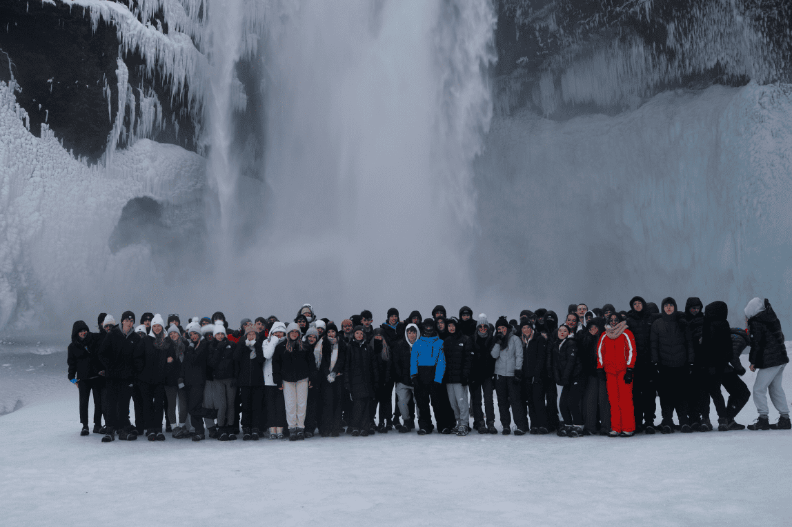 Students from Cheadle Hulme High School stand in front of Skógafoss waterfall in Iceland.